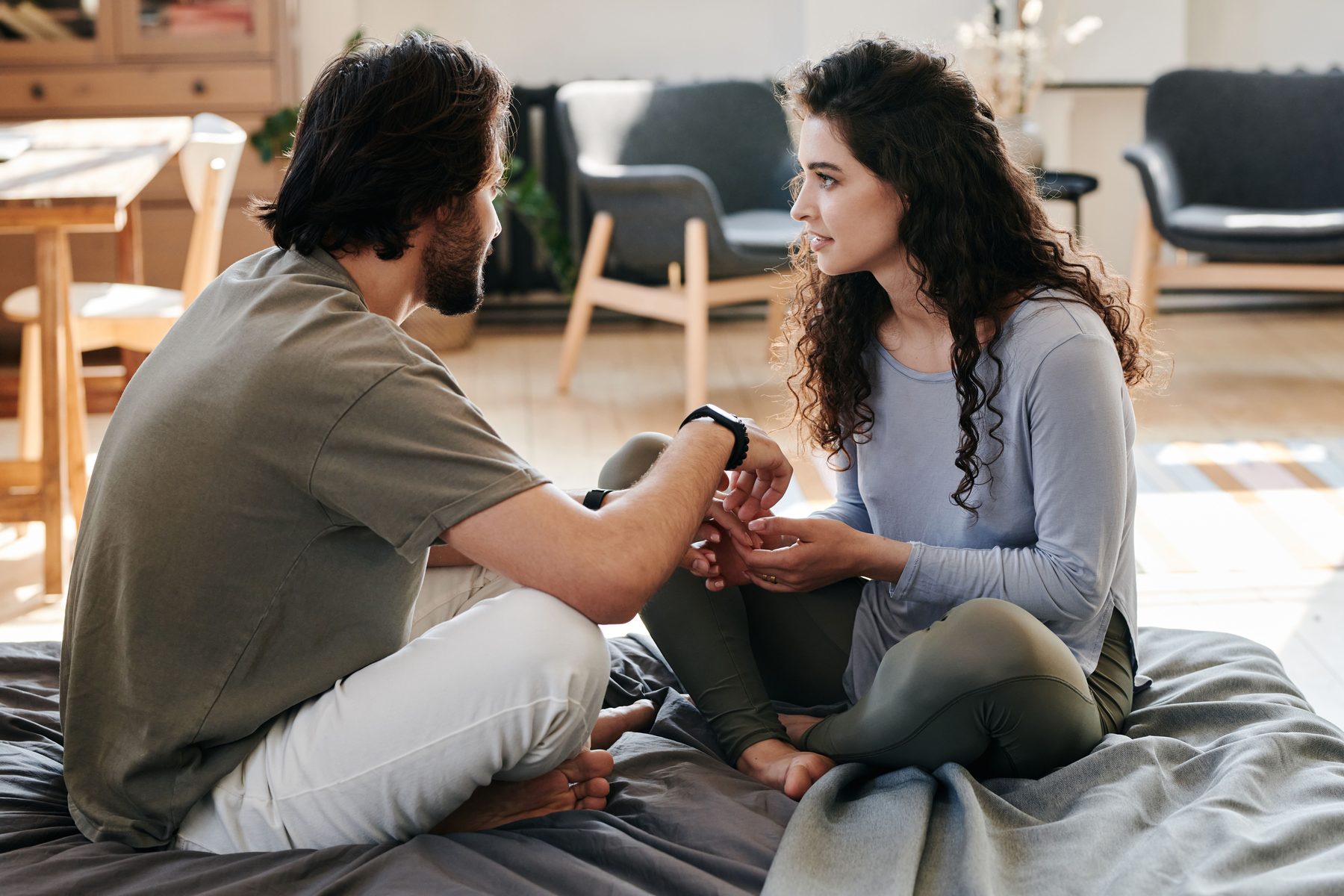 Two partners sitting together in conversation, hands touching
