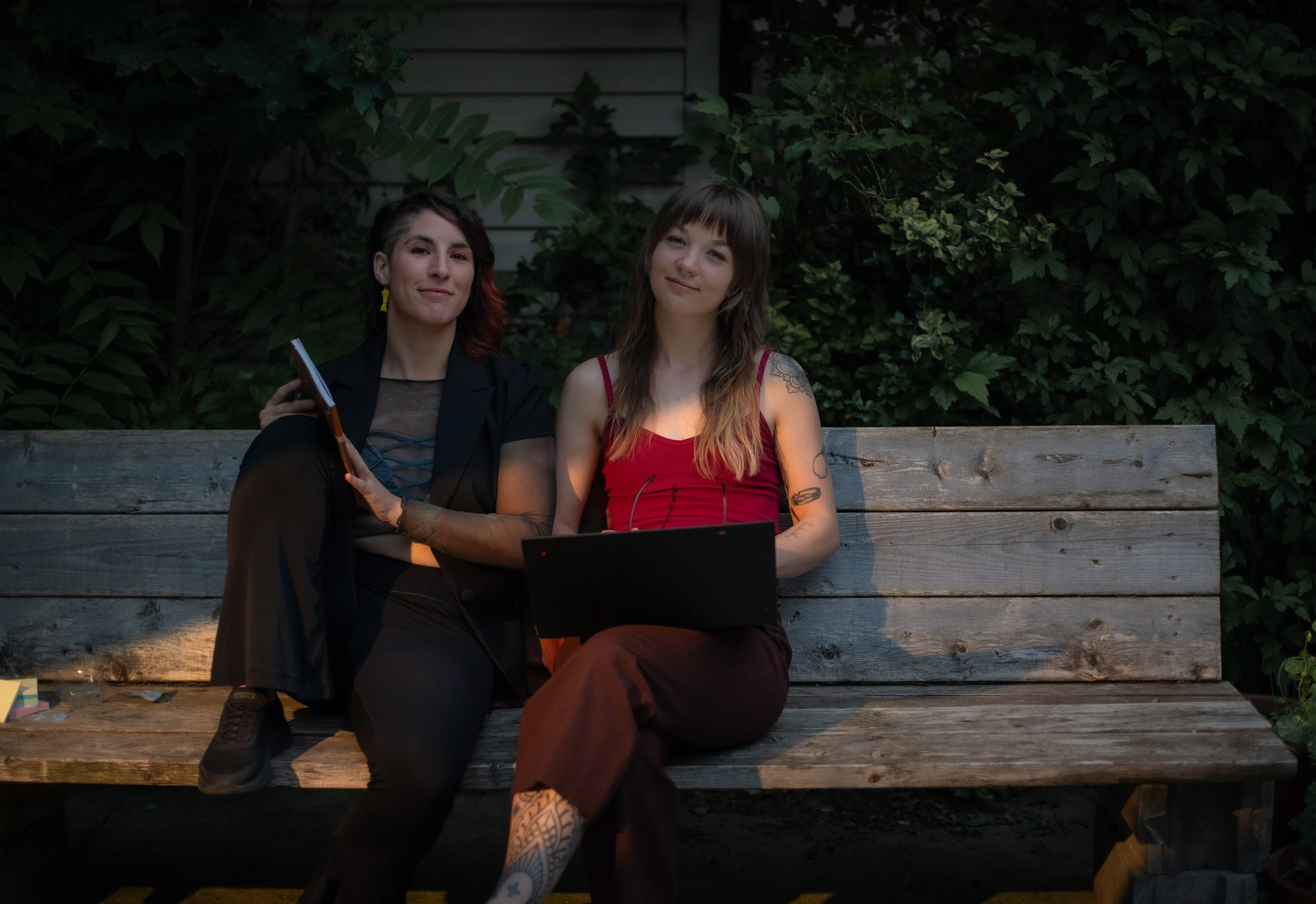 Isa and El sitting together on a bench in a garden